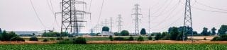 Image of high-tension power transmission lines over fields symbolising energy and power valuation and risk analytics